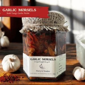 Glass jar of Spiso Garlic Morsels Kerala Garlic Pickle on a wooden surface with garlic cloves
